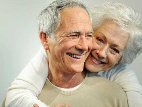 middle-aged male and female holding each other and smiling